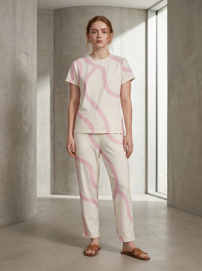 Woman wearing a pink and white patterned outfit in a minimalistic room.