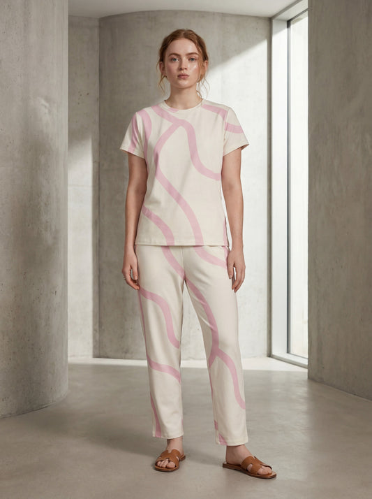 Woman wearing a pink and white patterned outfit in a minimalistic room.